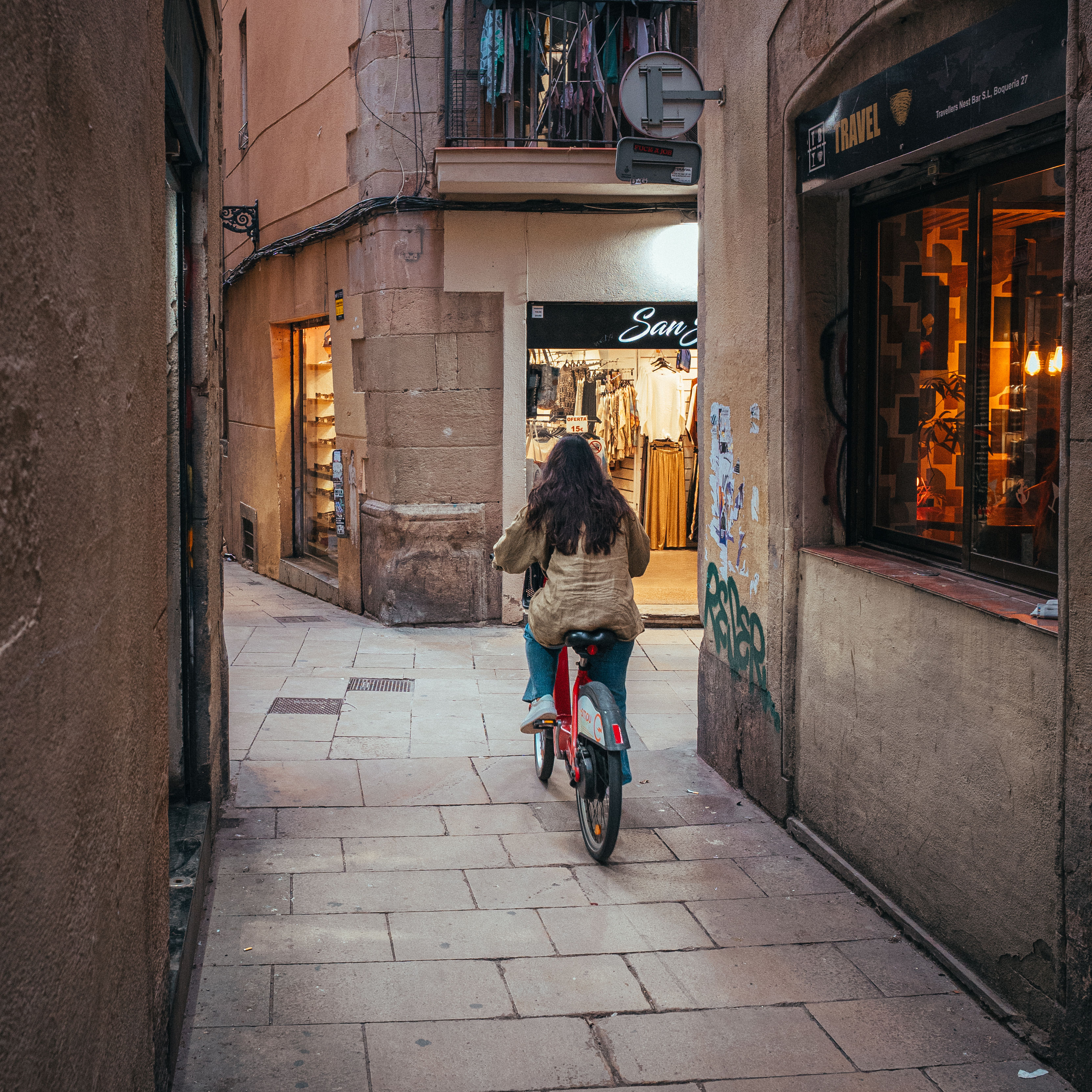Woman on a red bike cycling through a narrow Gothic Quarter alley, Barcelona