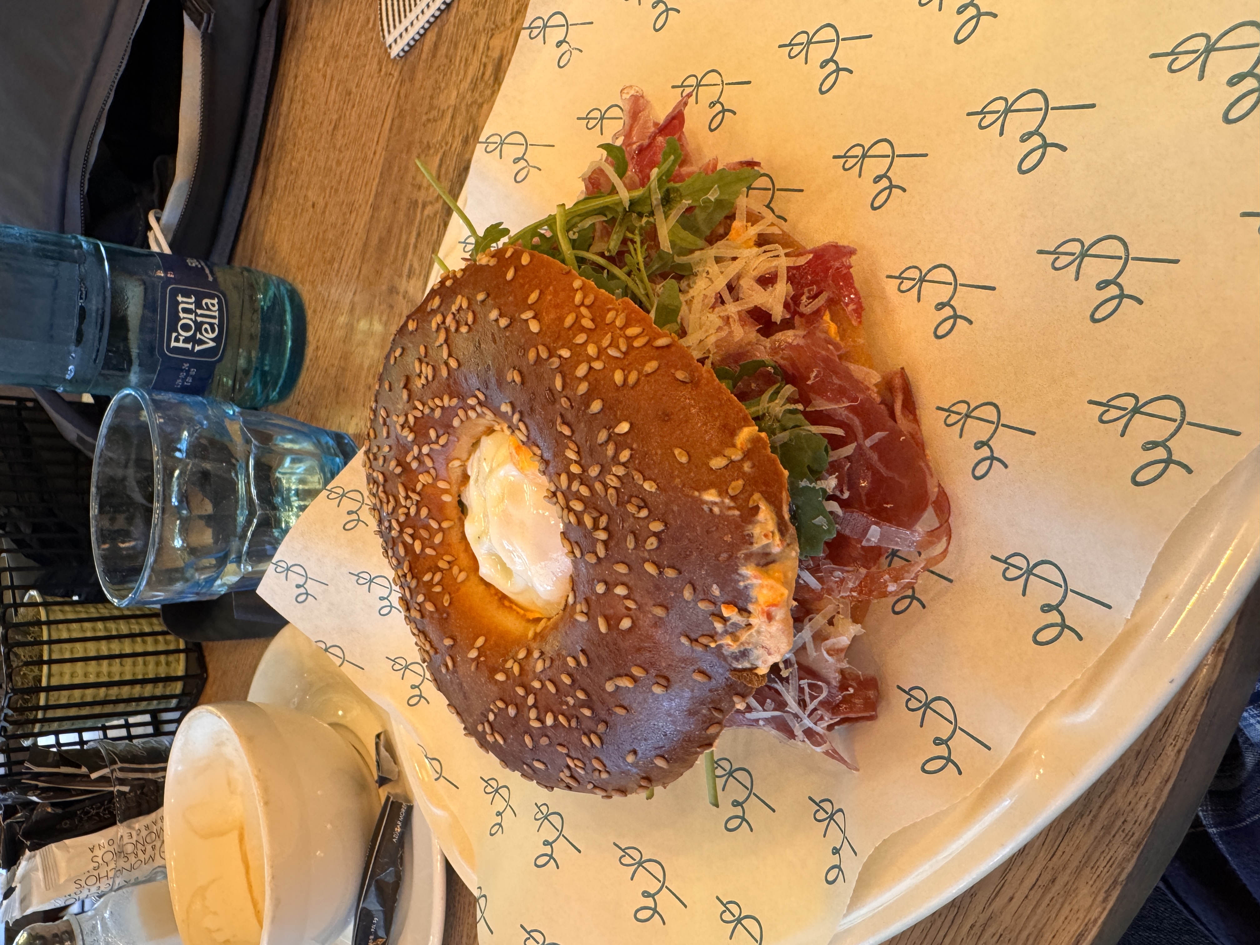 A jamon and egg bagel sandwich on a wooden board at Cafe Europa, Barcelona