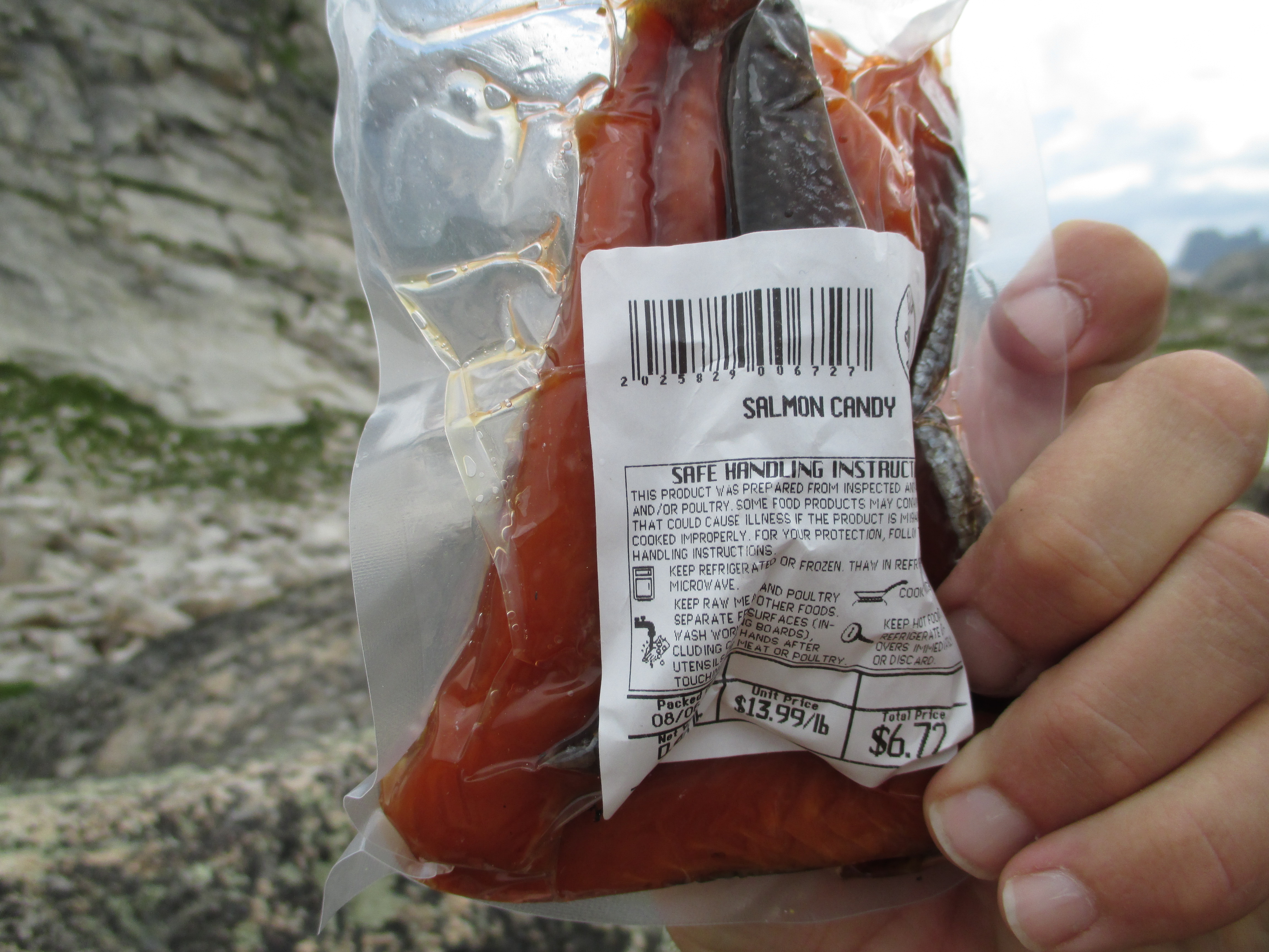 A packet of salmon candy held up against the rocky alpine backdrop at Fossil Lake