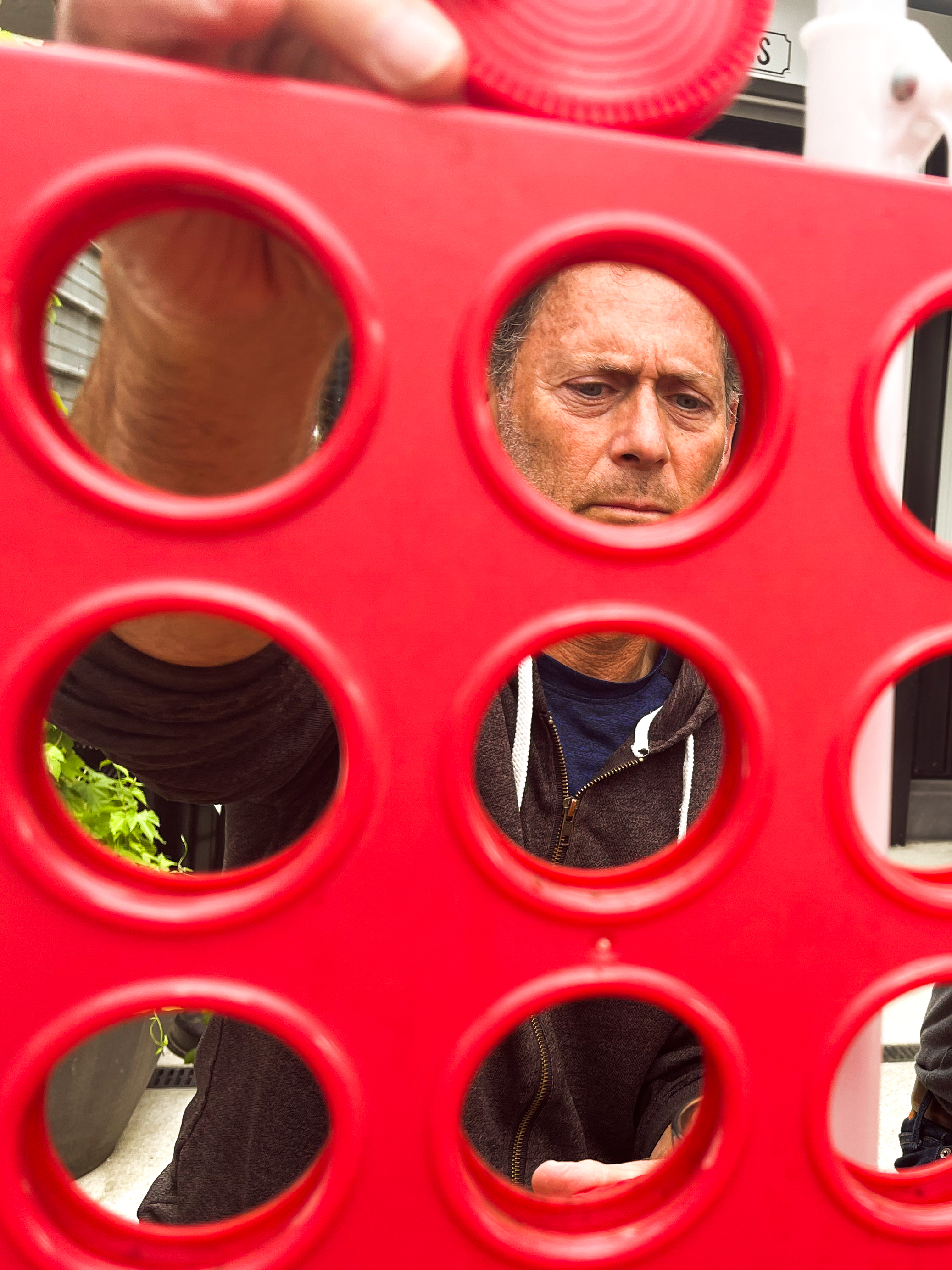 A man peers with absolute focus through the holes of a giant red Connect Four board at Rhein Haus in Seattle's Capitol Hill neighborhood